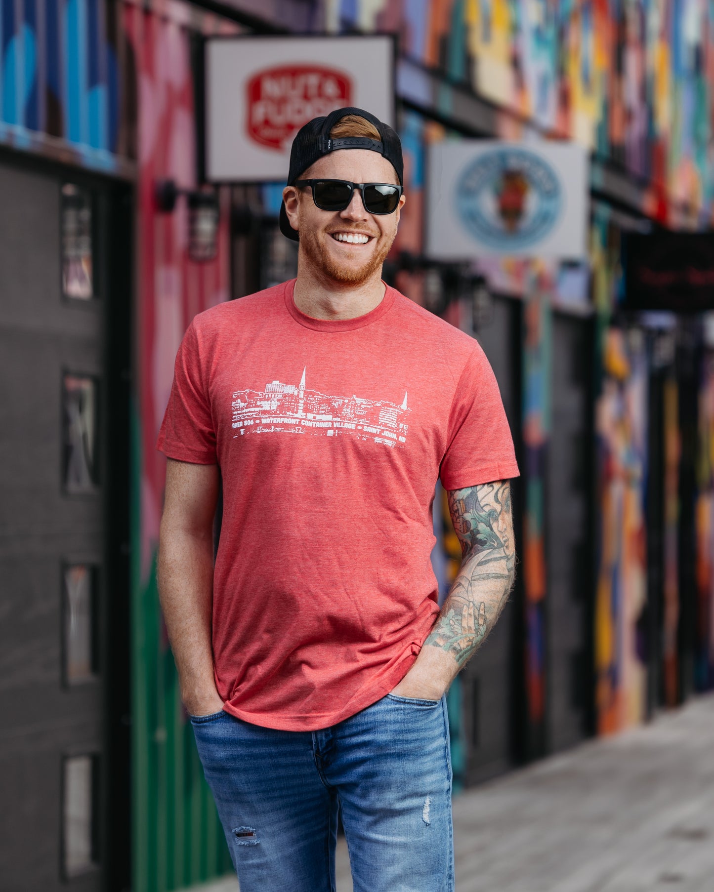 Navy, Sky Blue, Orange, Red, Charcoal, Brown, Purple or Green t-shirts featuring the Saint John New Brunswick Cityscape. AREA 506 Waterfront Container Village Saint John NB text printed in white.