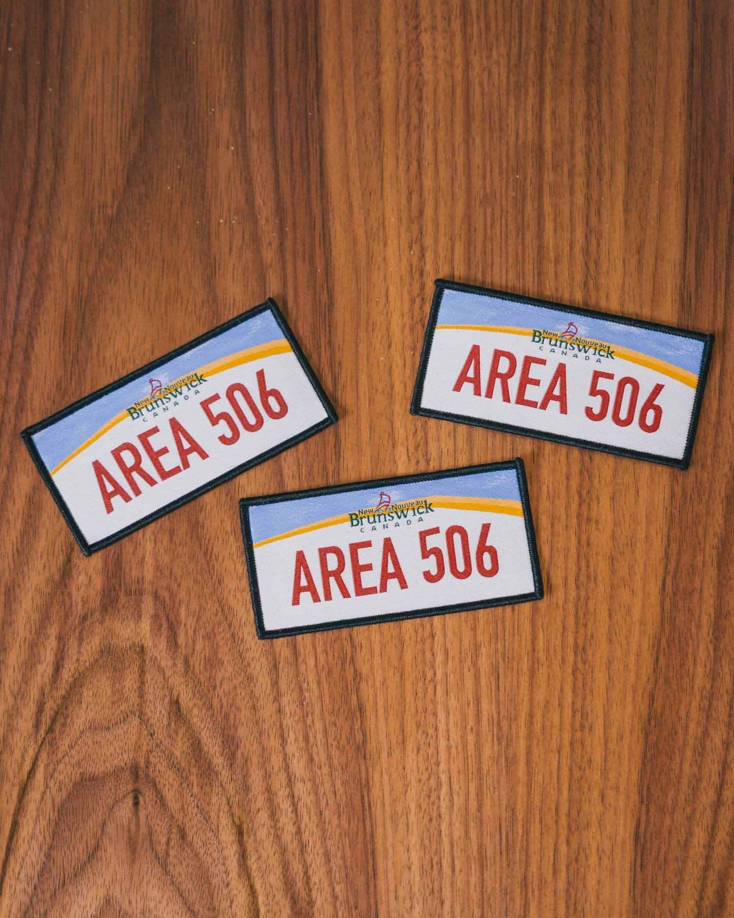 Three 'AREA 506' patches on a wooden surface