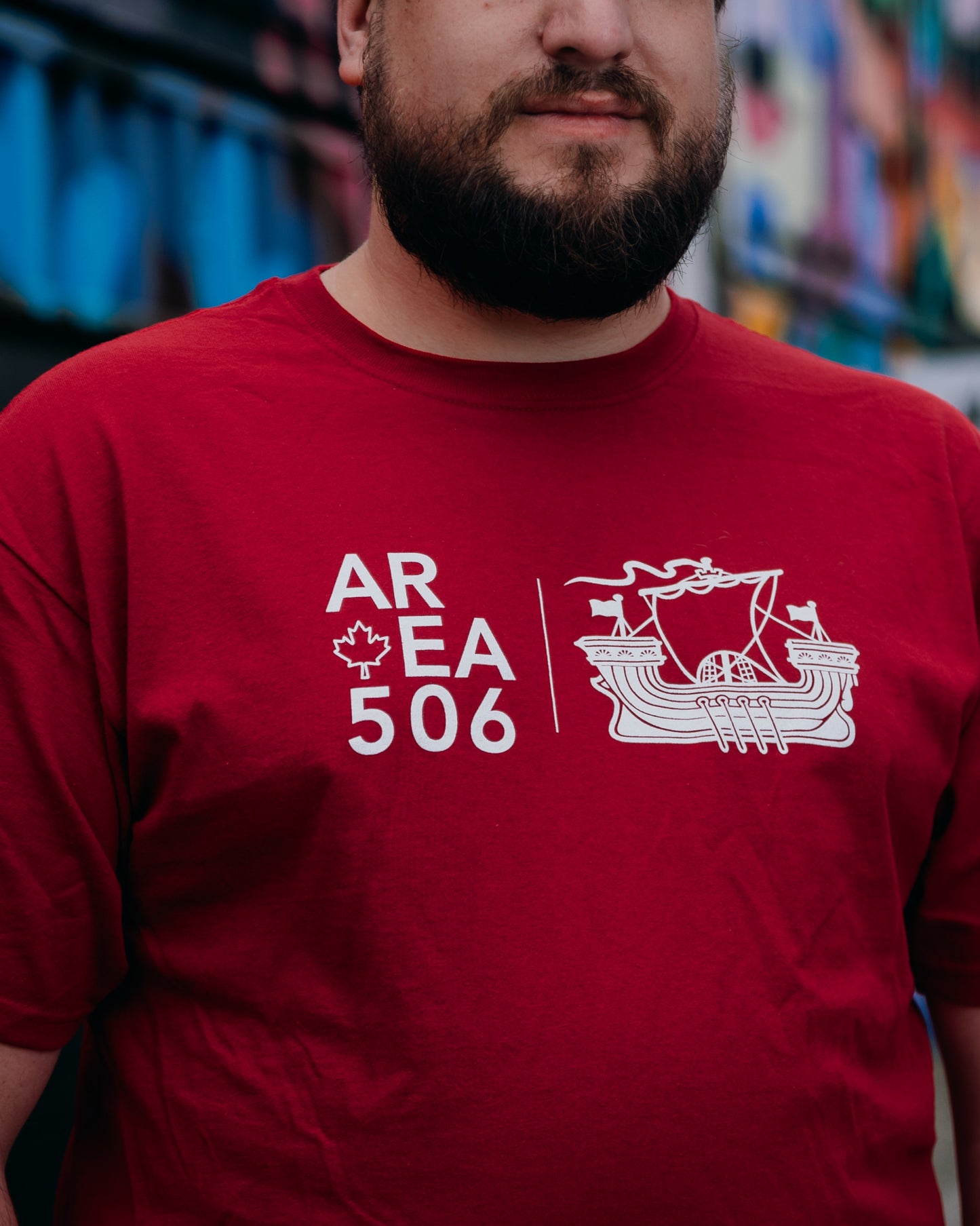 Person wearing a red t-shirt with white 'AREA 506' ship logo design