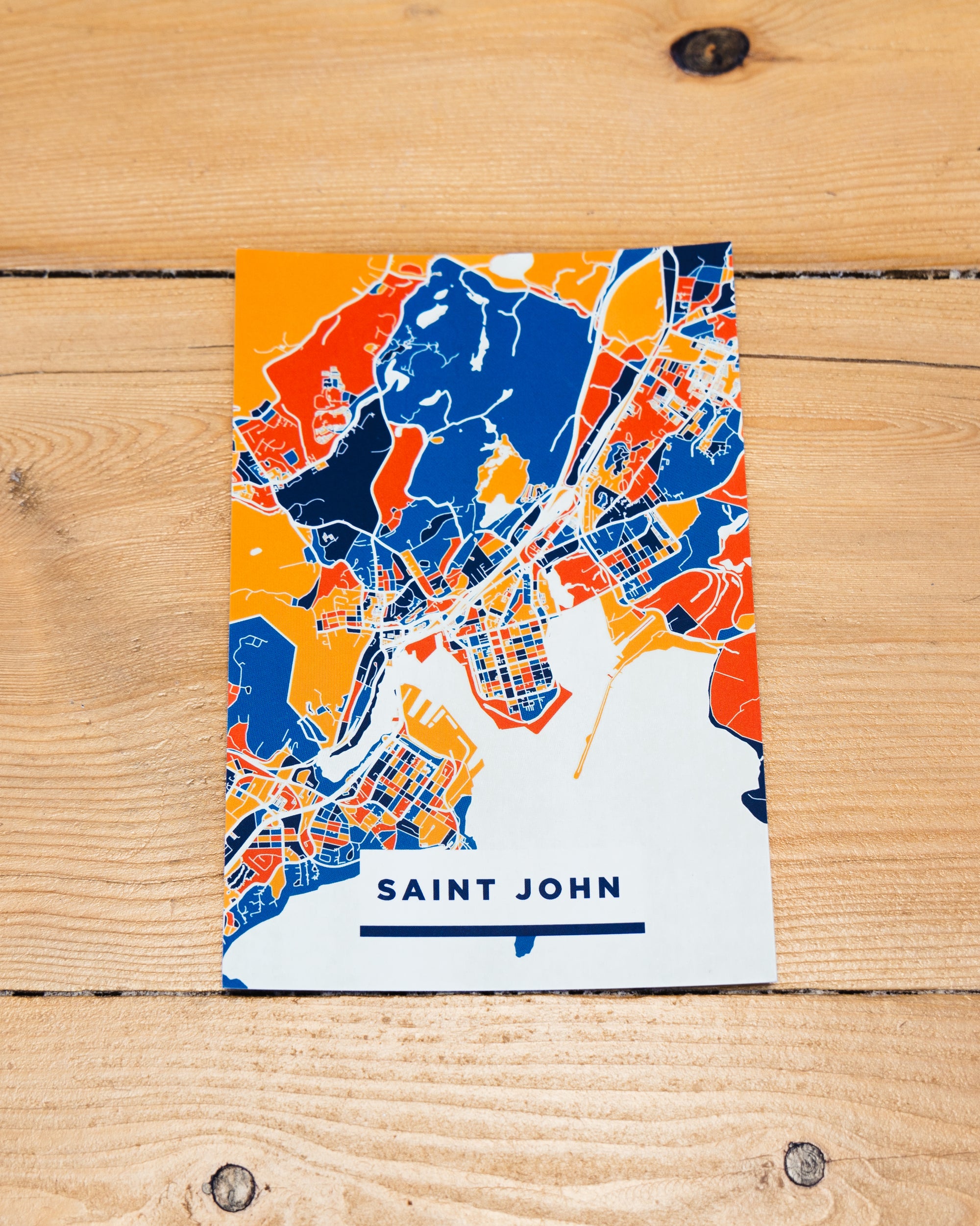 Light orange postcard with festive waterfront landmarks, with dark blue Saint John text.