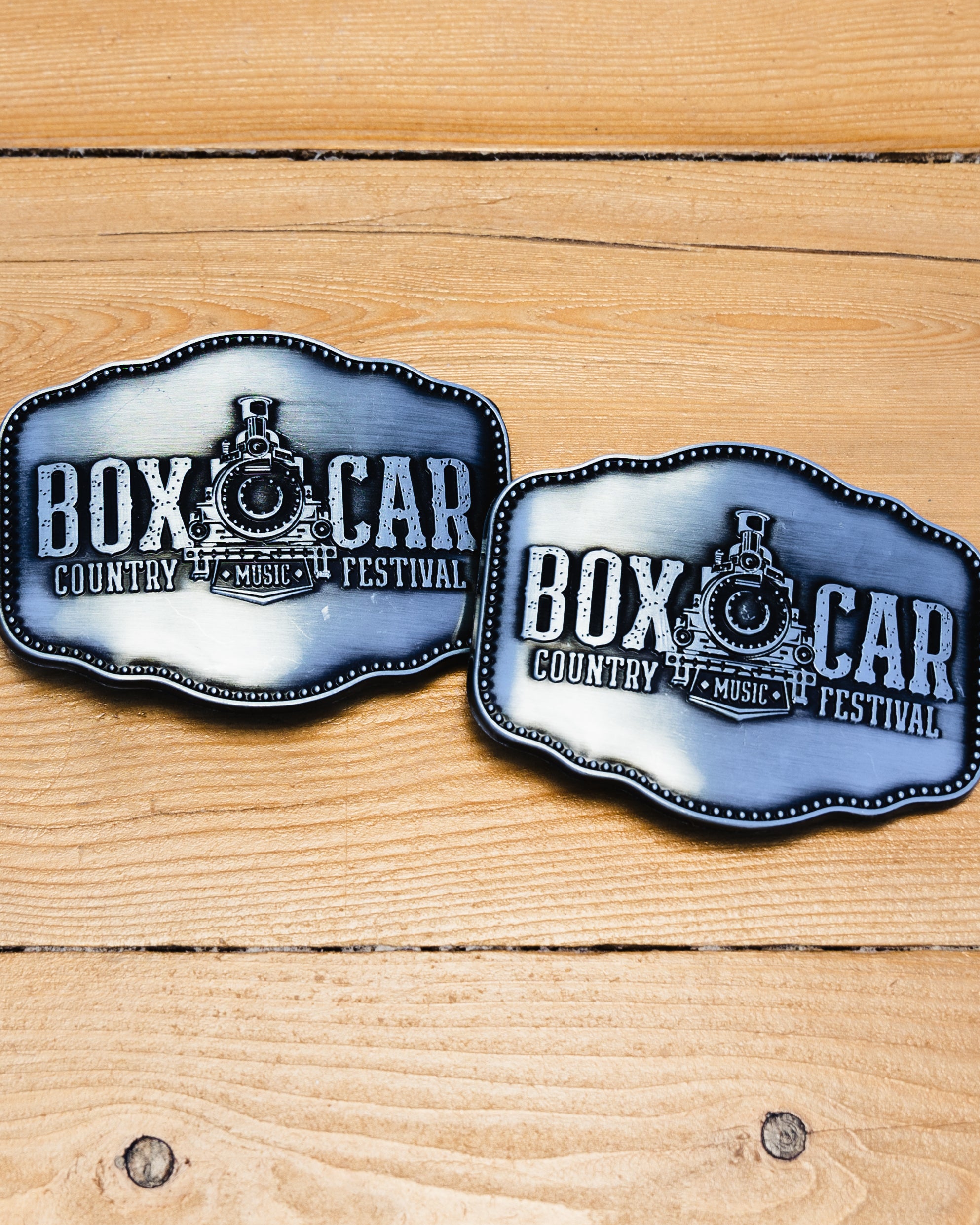 Silver belt buckle with the Boxcar Country Music Festival train logo.