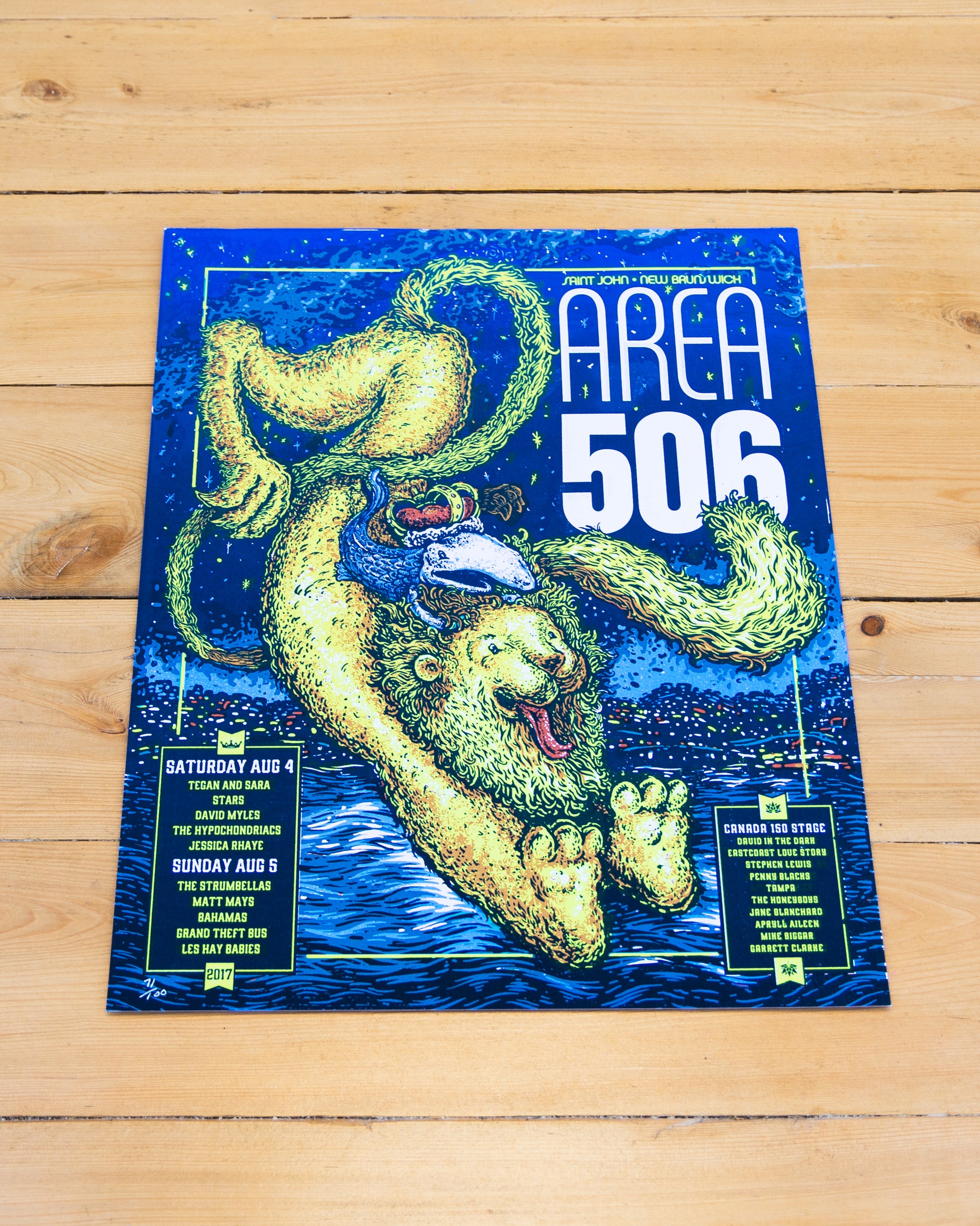 Dark blue poster with festive waterfront landmarks. Featuring the artist lineup from the 2017 AREA 506 Music Festival- including; Saturday Aug 4; Tegan and Sara, Stars, David Myles, The Hypochondriacs, and Jessica Rhaye. Sunday Aug 5 The Strumbellas, Matt Mays, Bahamas, Grand Theft Bus and Les Hay Babies. Canada 150 Stage; David in the Dark, Eastcoast Love Story, Stephen Lewis, Penny Blacks, Tampa, The Honeyboys, Jane Blanchard, Apryll Aileen, Mike Biggar, and Garrett Clarke.