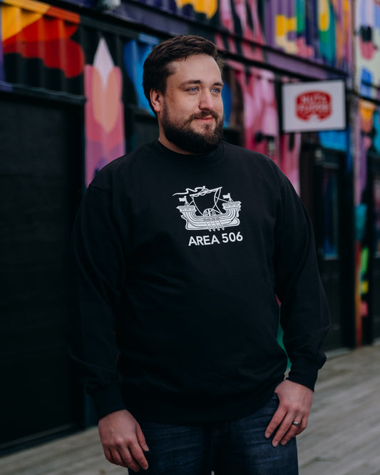 Man wearing a black sweatshirt with 'AREA 506' design in front of a colourful mural.