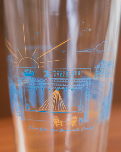 Clear glass tumbler with blue etched design of a bridge and chairs on a wooden surface