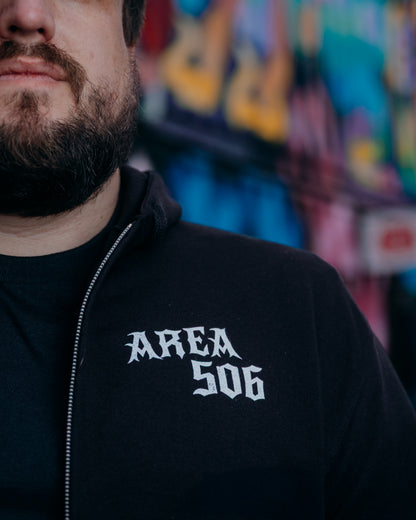 Person wearing a black hoodie with 'AREA 506' text, blurred colourful background