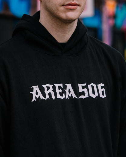 Person wearing a black hoodie with 'AREA 506' printed on it, blurred colourful background