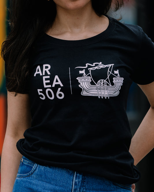 A woman wearing a short-sleeved black t-shirt with 'AREA 506' and a sailboat logo on the front.