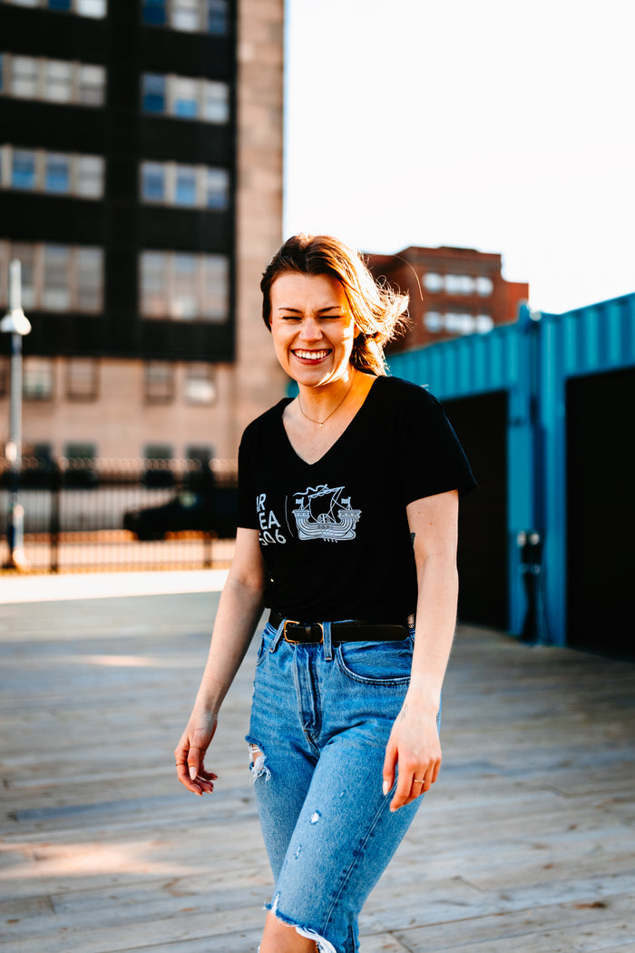 Light blue or black V-neck t-shirt with the AREA 506 galley ship logo printed in white on the full chest.